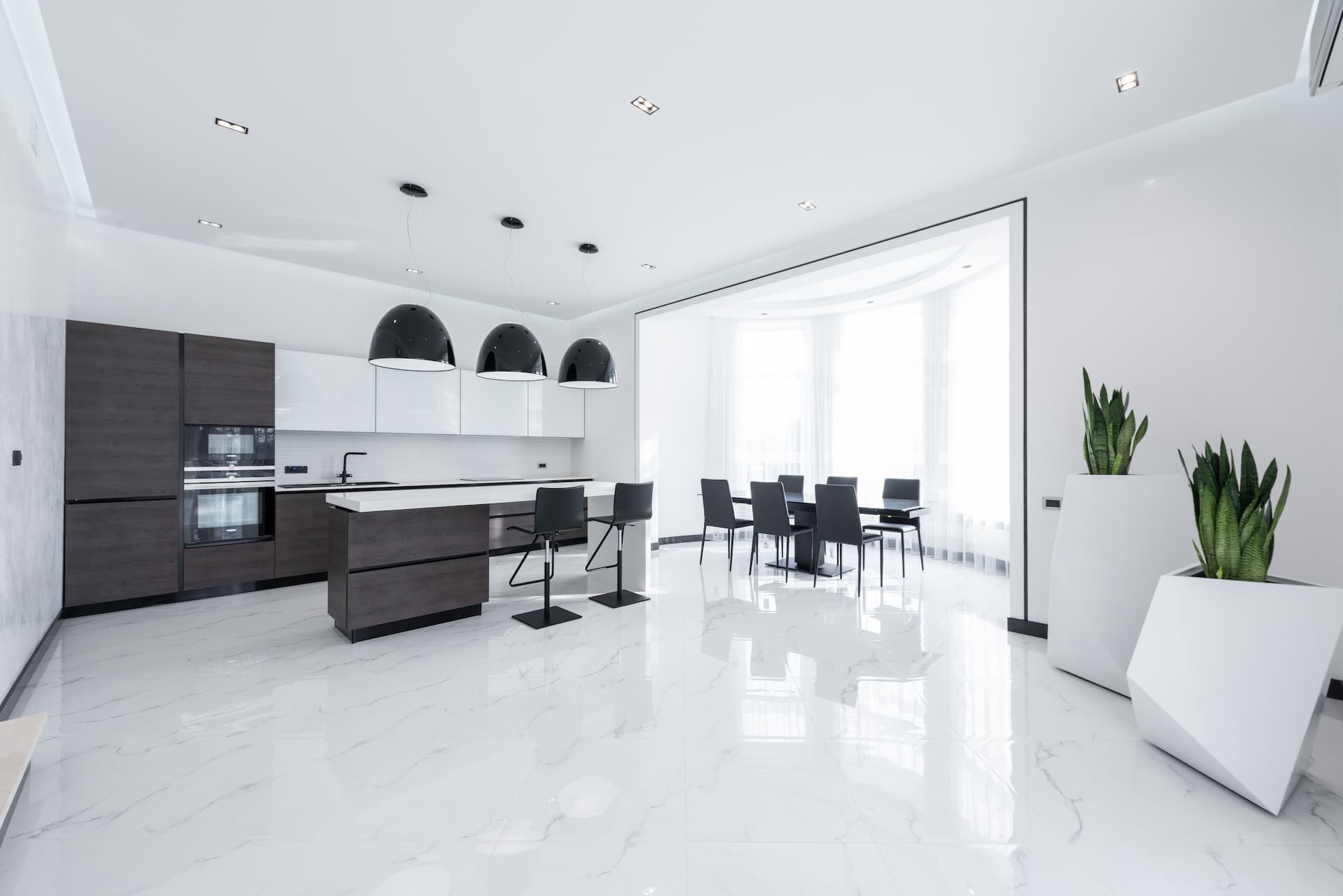 Cocina abierta al salón con suelo de piedra natural en tono blanco.